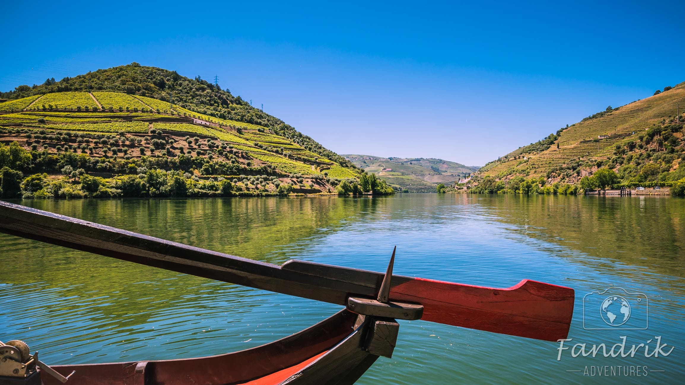 Lenkruder eines roten Bootes, das auf dem Douro Fluss durchs Tal schippert