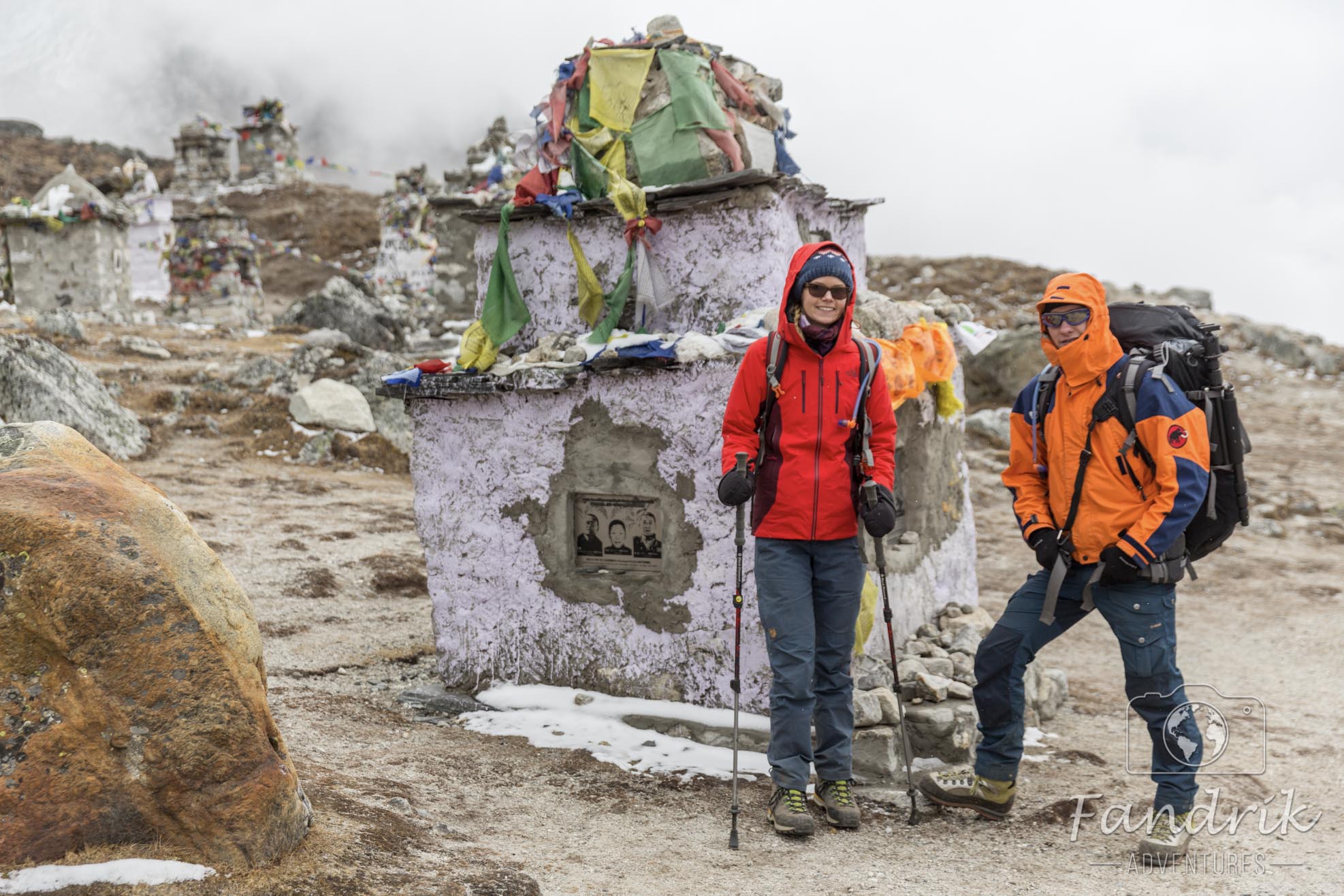 Zwei Personen stehen vor einem Grabstein der Gedenkstätte verstorbener Bergsteiger in Nepal.